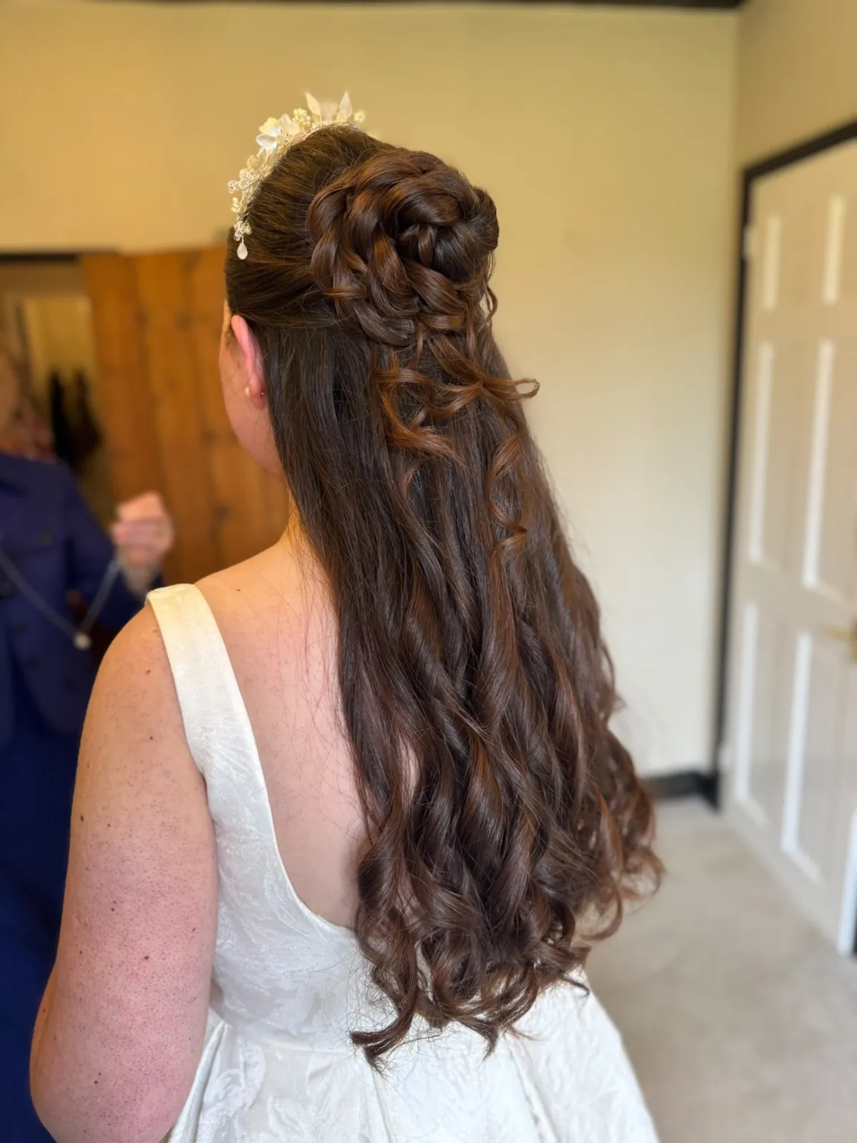 Long half-up bridal curls with a braided rosette and floral hair vine by Be Bridal