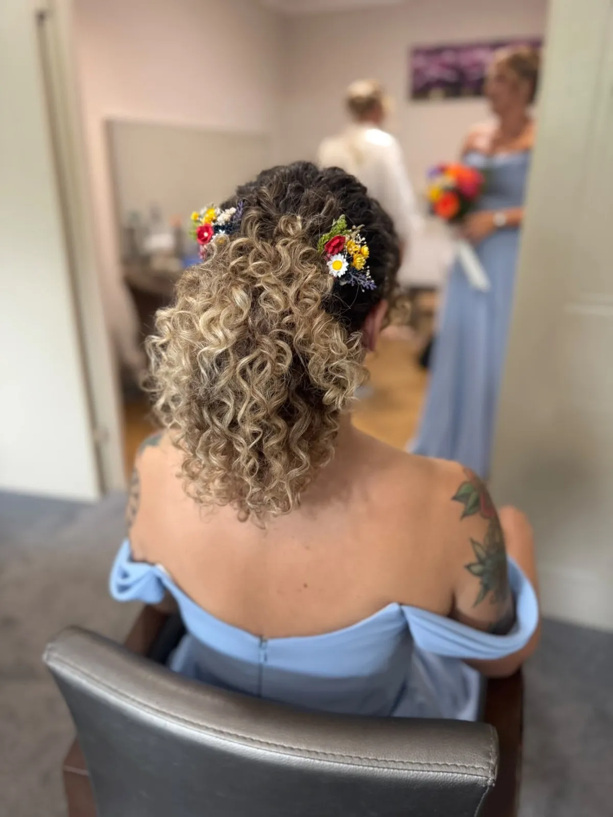 Naturally curly bridal updo with colourful wildflower hair pins by Be Bridal