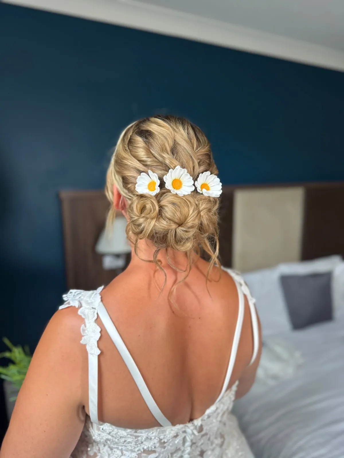 Blonde textured bridal updo with daisy hair pins by Be Bridal