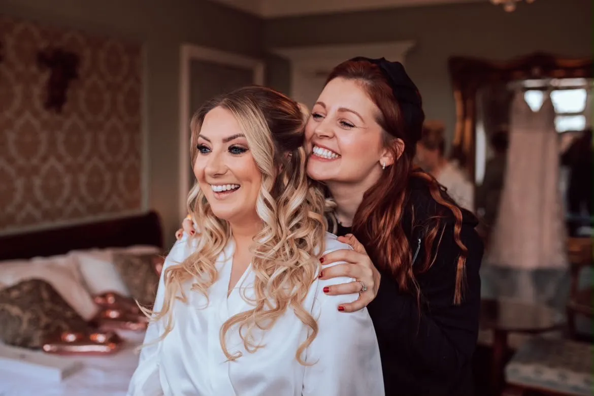 Bride embracing her hair and makeup artist after getting ready by Be Bridal