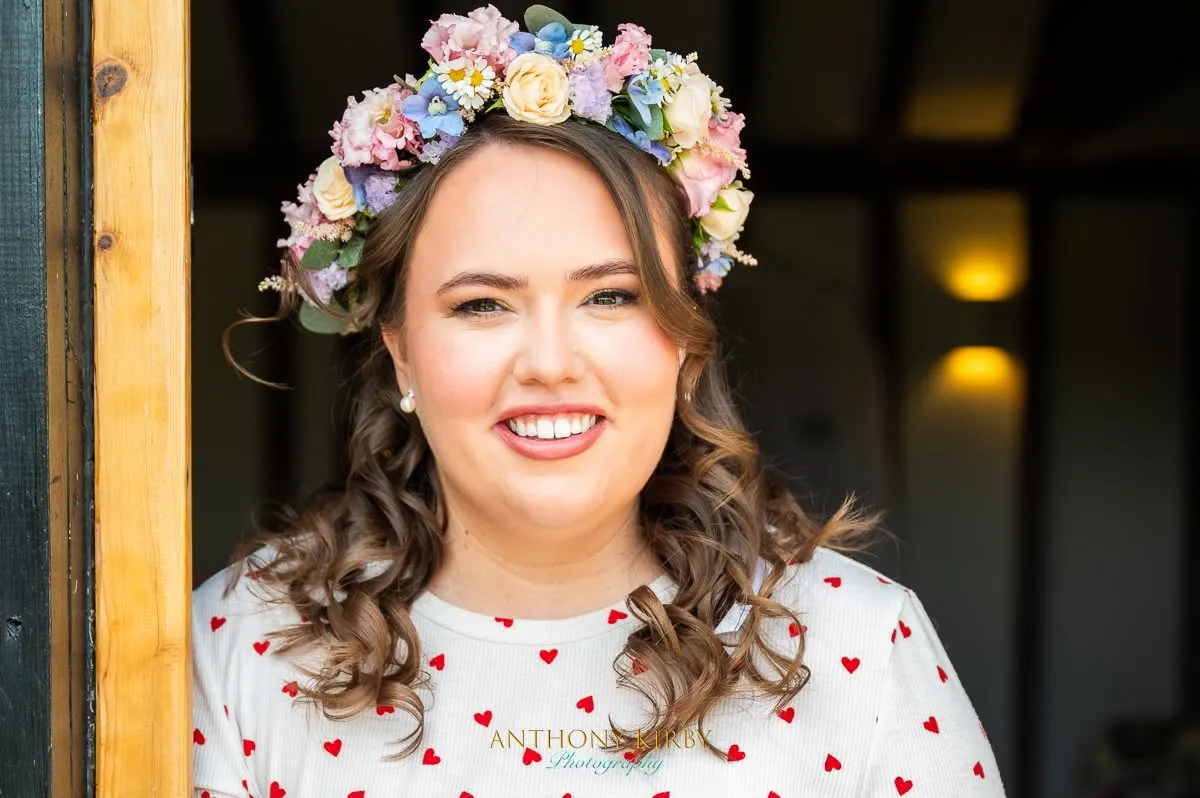 Smiling bride with a pastel flower crown and soft curls by Be Bridal