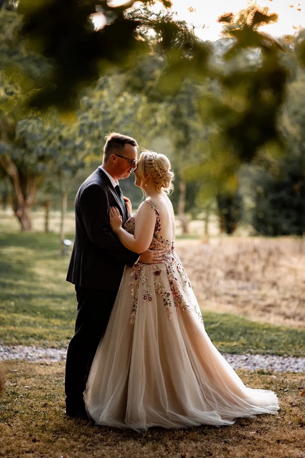 Bride with a braided updo embracing her groom at golden hour by Be Bridal