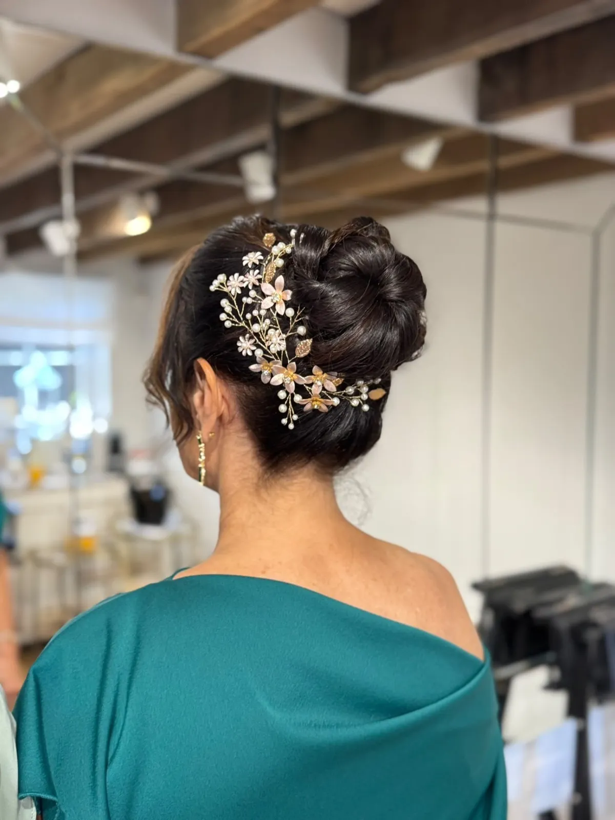 Elegant low bun with a pearl and blush floral hair vine by Be Bridal