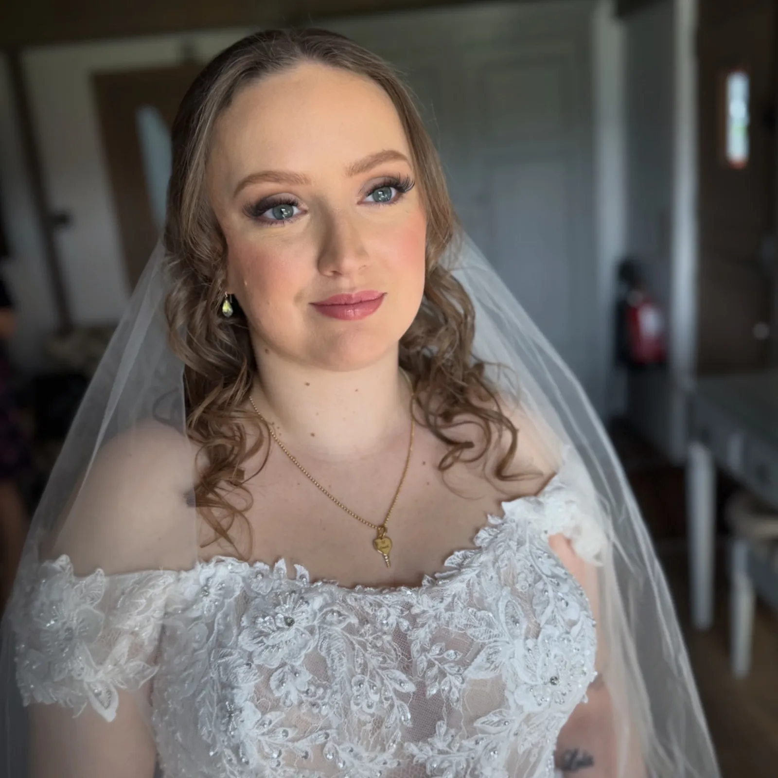 Bride in a lace veil with soft glam makeup and loose curls by Be Bridal