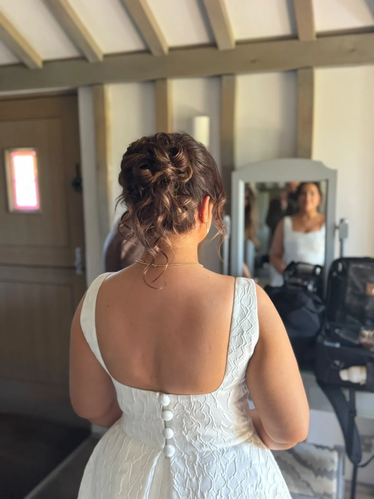 Bride's textured curly high updo in a square-back gown by Be Bridal