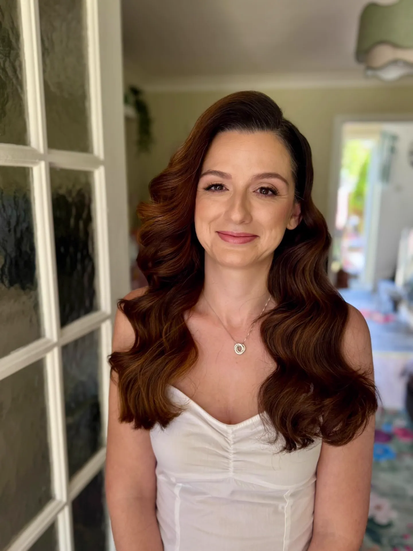 Bride with long auburn Hollywood waves and soft glam makeup by Be Bridal