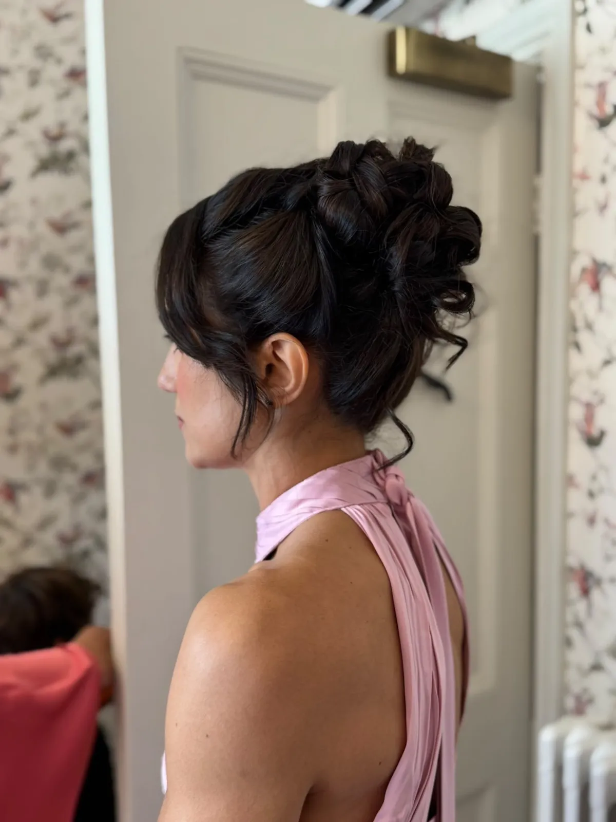 Voluminous textured updo for a guest in a blush halter dress by Be Bridal