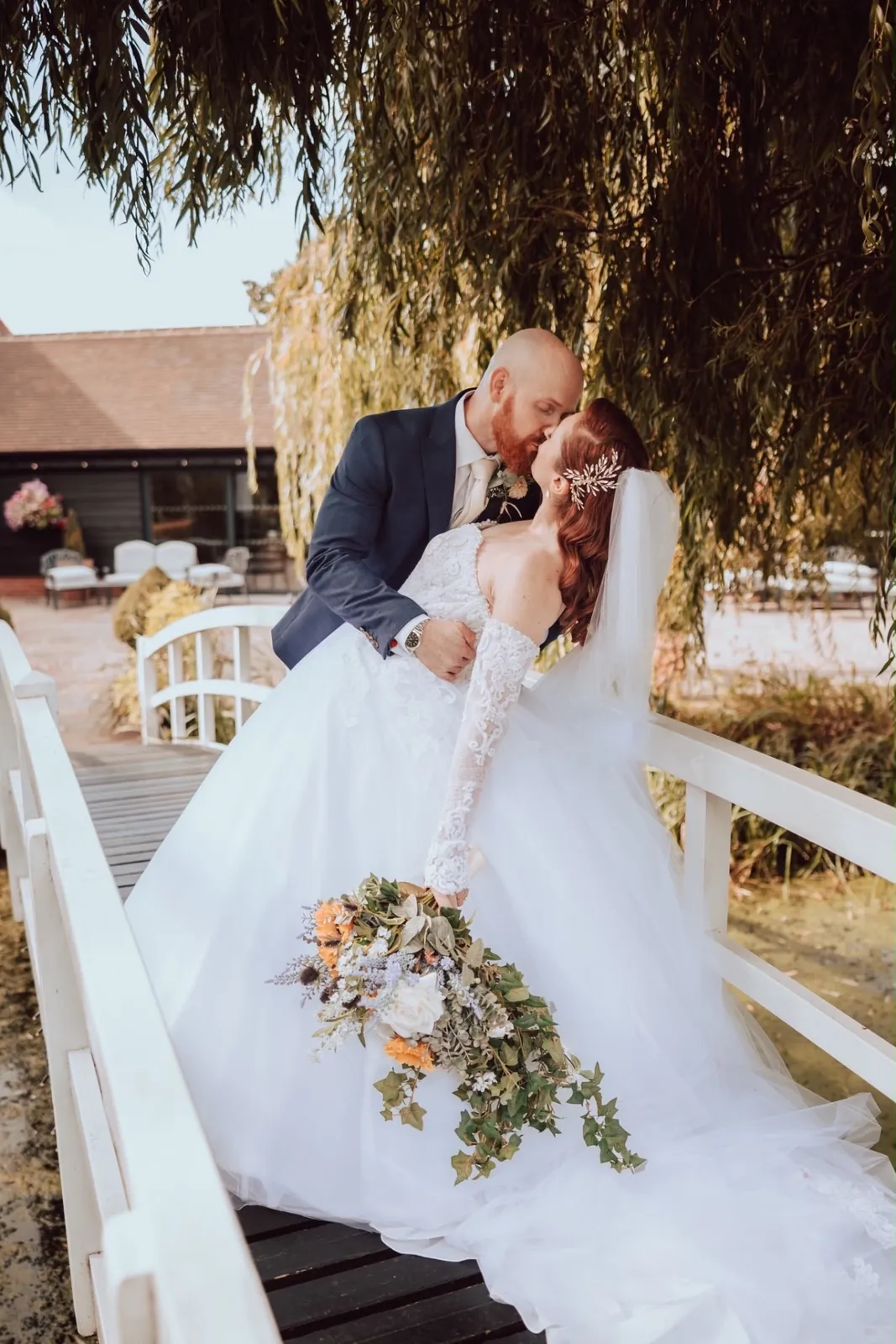 Bride and groom sharing a kiss on a footbridge after the ceremony by Be Bridal