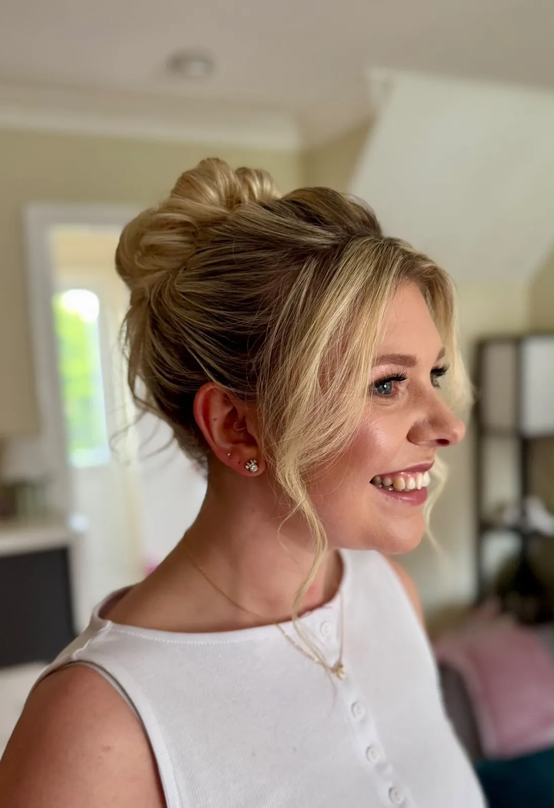 High textured blonde bun with face-framing tendrils and glowing makeup by Be Bridal