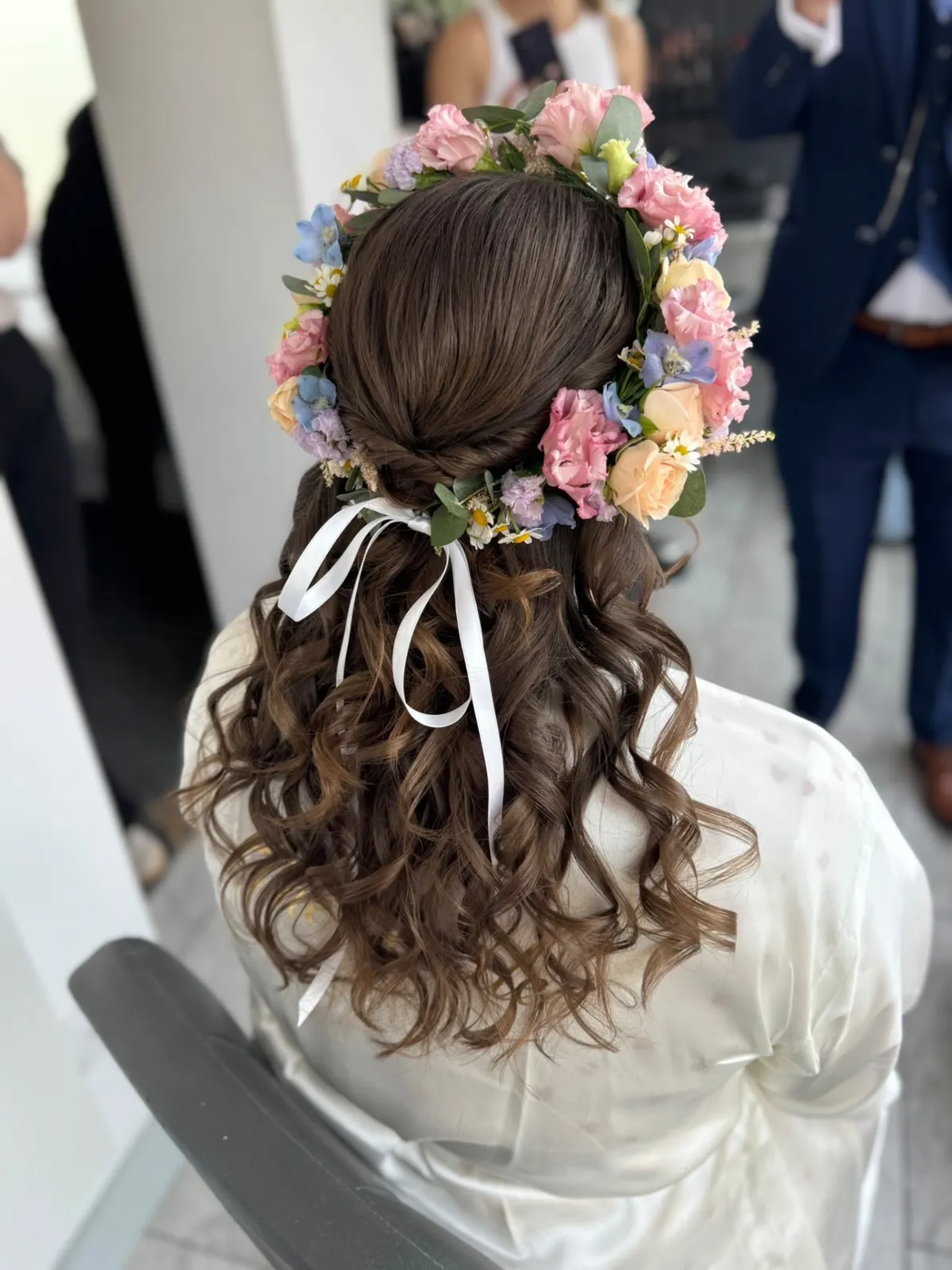 Half-up bridal curls with a pastel fresh flower crown and white ribbon by Be Bridal