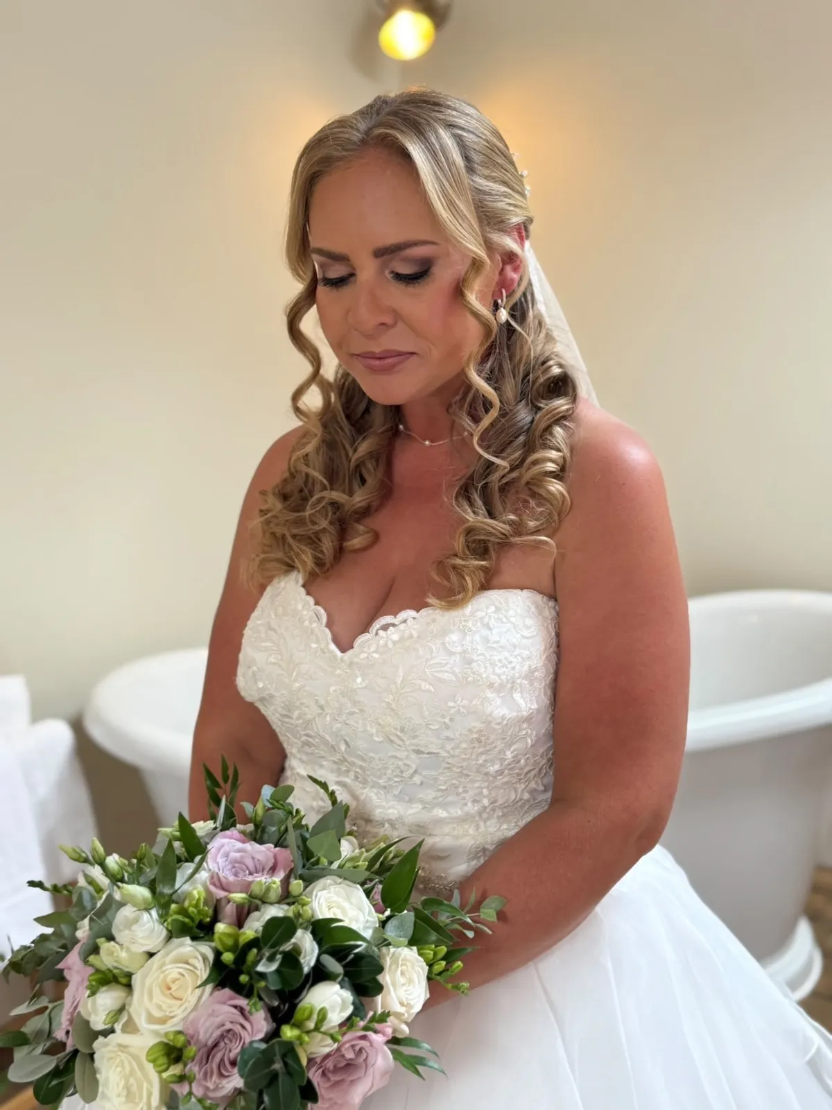 Bride with Hollywood waves and veil holding a lilac and ivory bouquet by Be Bridal