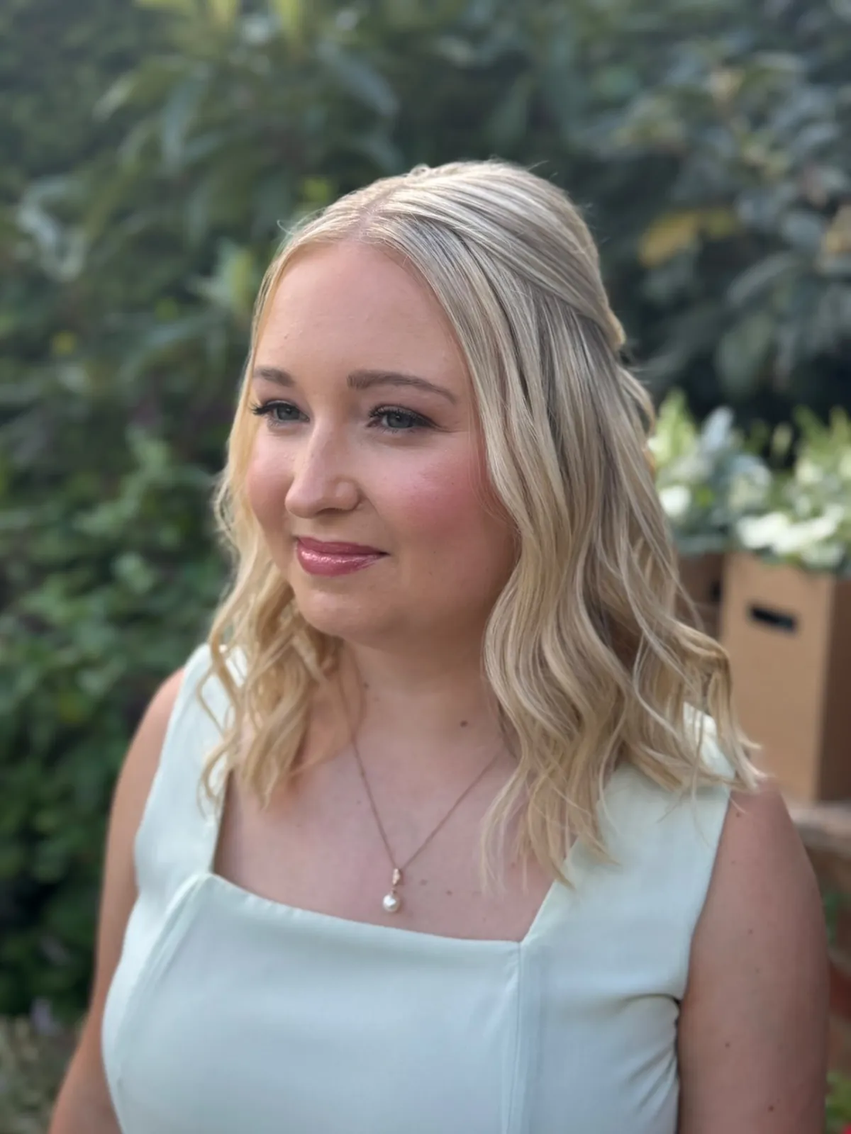 Bride with styled waves and soft makeup in a green garden by Be Bridal