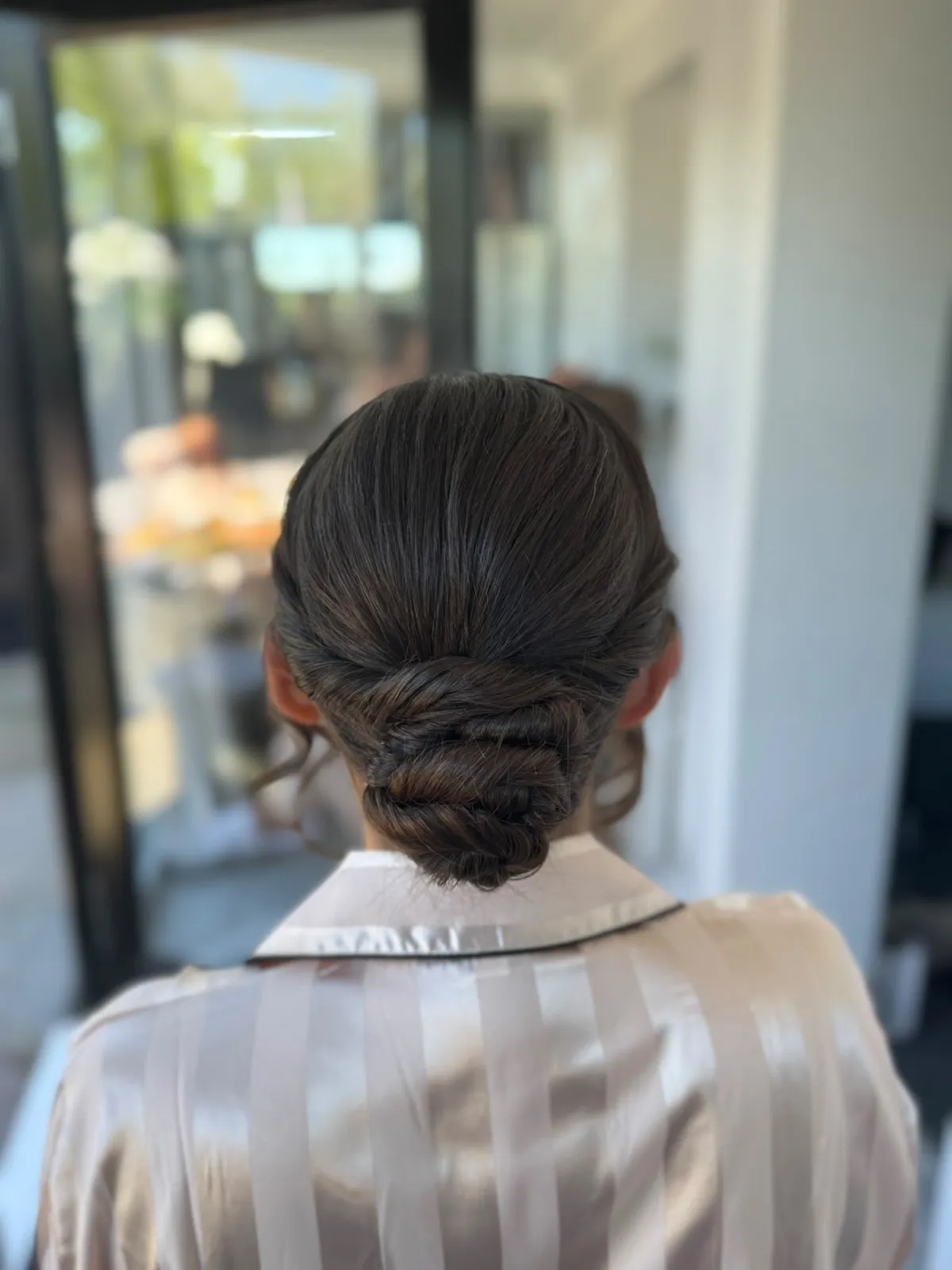 Sleek dark twisted low bun by Be Bridal