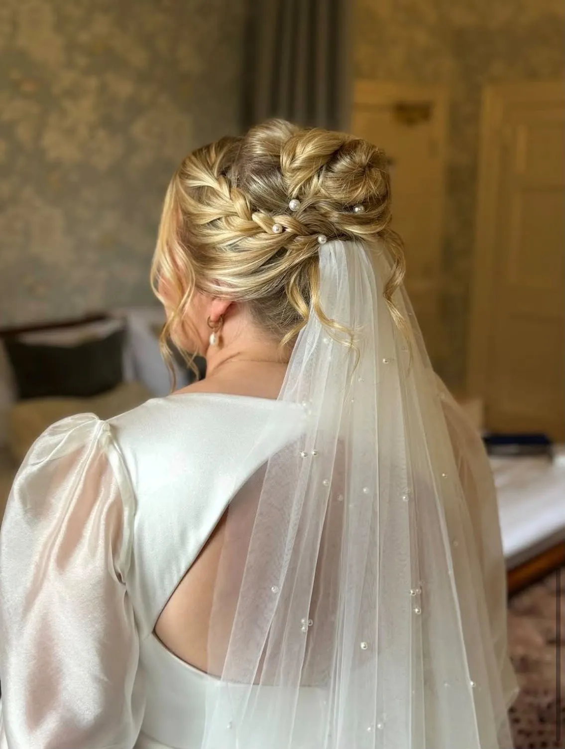 Blonde braided bridal updo with pearl pins and a pearl-scattered veil by Be Bridal
