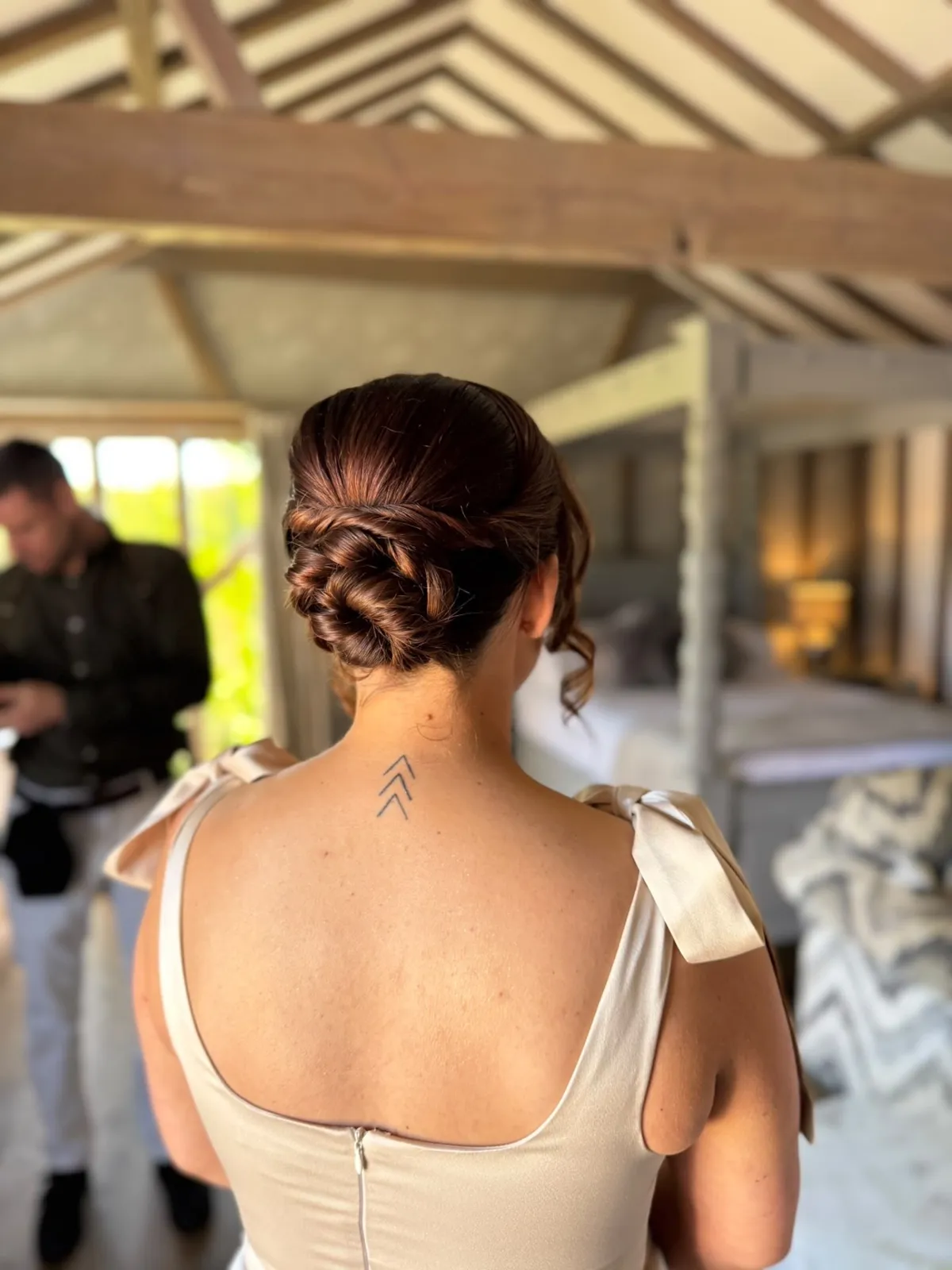 Sleek twisted low bun on a bride in an open-back gown by Be Bridal